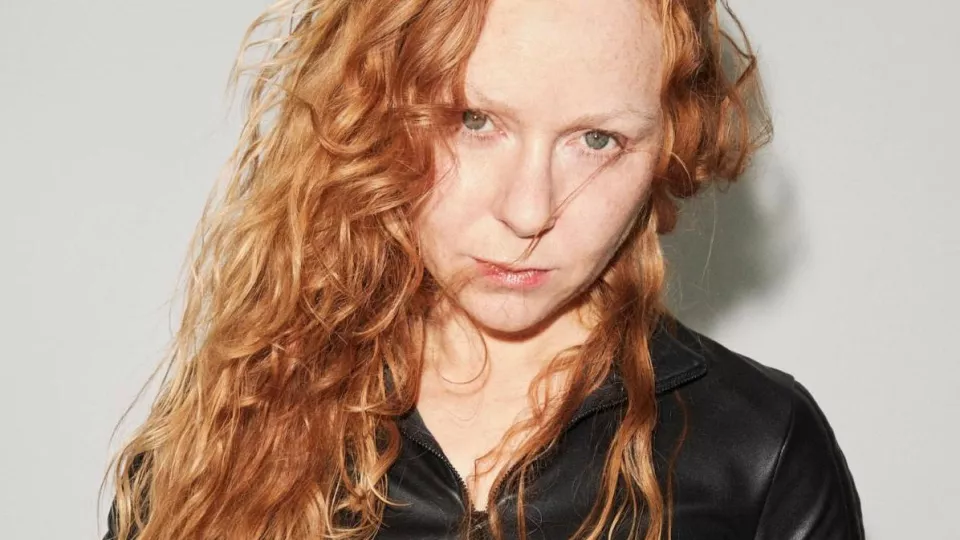 Photo of a woman with red curly hair and a black jacket.