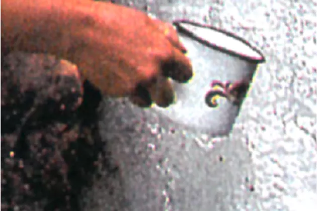en hand som håller i en mugg mot grå bakgrund